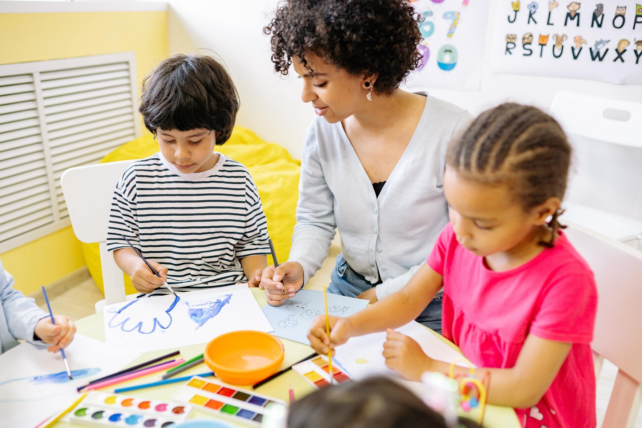 Children drawing while teacher observes